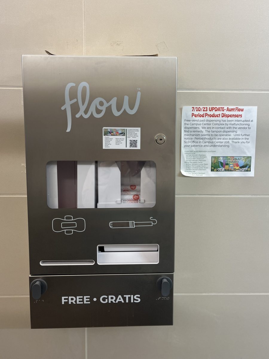 The Aunt Flow period product dispenser in the University of Hawaii at Mānoa Warrior Recreation Center bathroom is among other malfunctioning dispensers across the Mānoa Campus Center. 

Audio Description: A large metal period product dispenser hangs on the wall. The name flow appears across the top in a cursive font. A clear screen shows the period products inside. An drawing outline of a pad is on the middle right, with an outline drawing of a tampon on the middle left. Two buttons are beneath the dispensing slots. The words FREE . GRATIS appear on the bottom. Next to the dispenser is a sign that reads: 7/10/23 UPDATE: Aunt Flow Period Product Dispensers. Free-vend pad dispensing has been interrupted at the Campus Center Complex by malfunctioning dispensers. We are in contact with the vendor to find a remedy. The tampon dispensing mechanism seems to be operable. Until further notice- Period Products are also available in the SLD Office in Campus Center 208. Thank you for your patience and understanding. Beneath these words are the Food Vault Hawaii logo and a list of Flow Free-Vend Dispenser Locations in a smaller font.