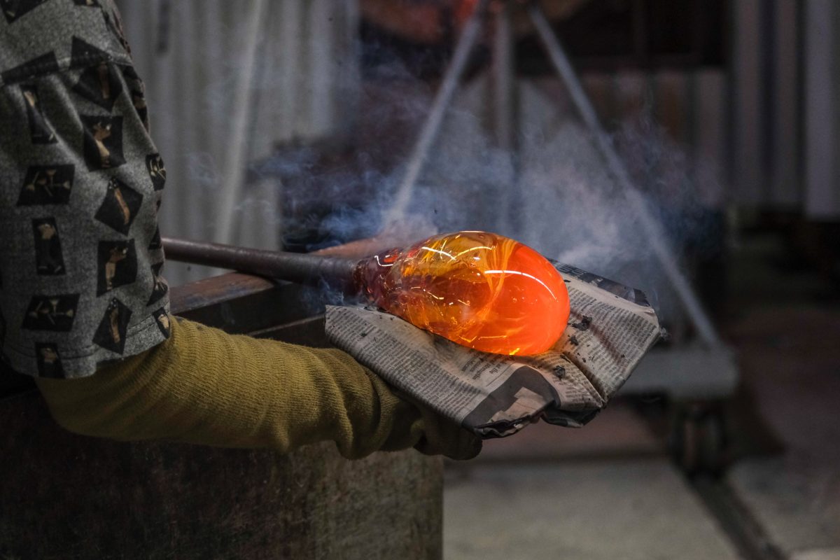 Noël Piechowski carefully handles the glowing hot glass as she rounds out the shape using newspaper soaked in water.