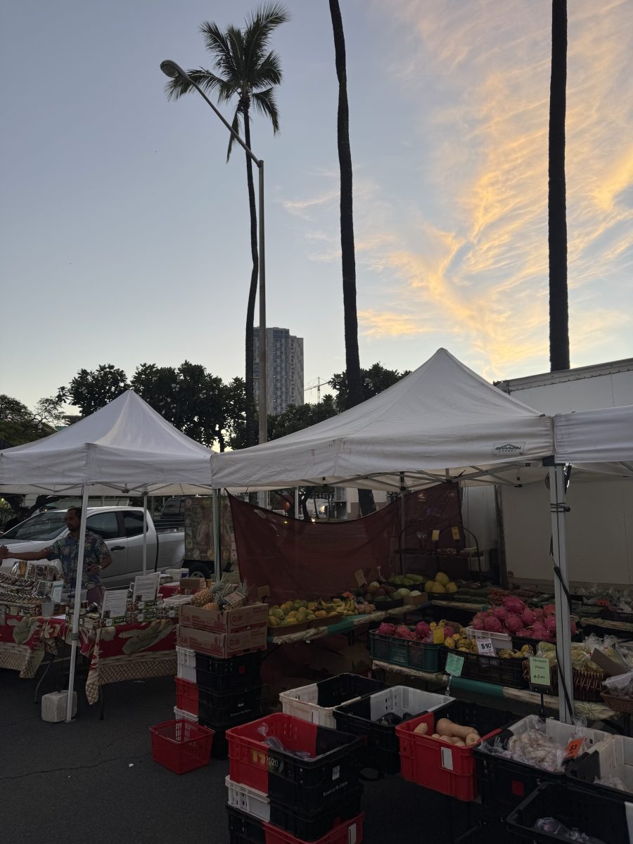 A lively scene at the Honolulu Farmers Market featuring colorful fresh produce and local food under the warm Hawaiian sun.