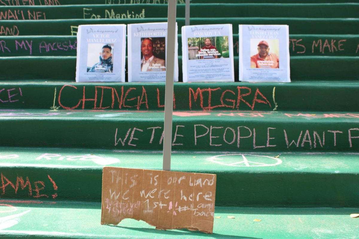 A hand-written sign demands land back in front of multiple memorial posters on the Campus Center steps.