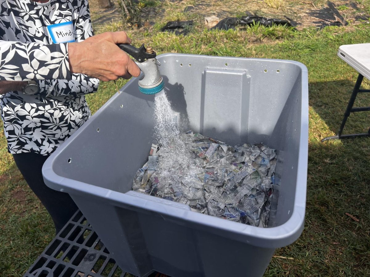 Mindy Jaffe shows students how to water their bins to allow their worms to survive, an action the students will have to perform daily.
