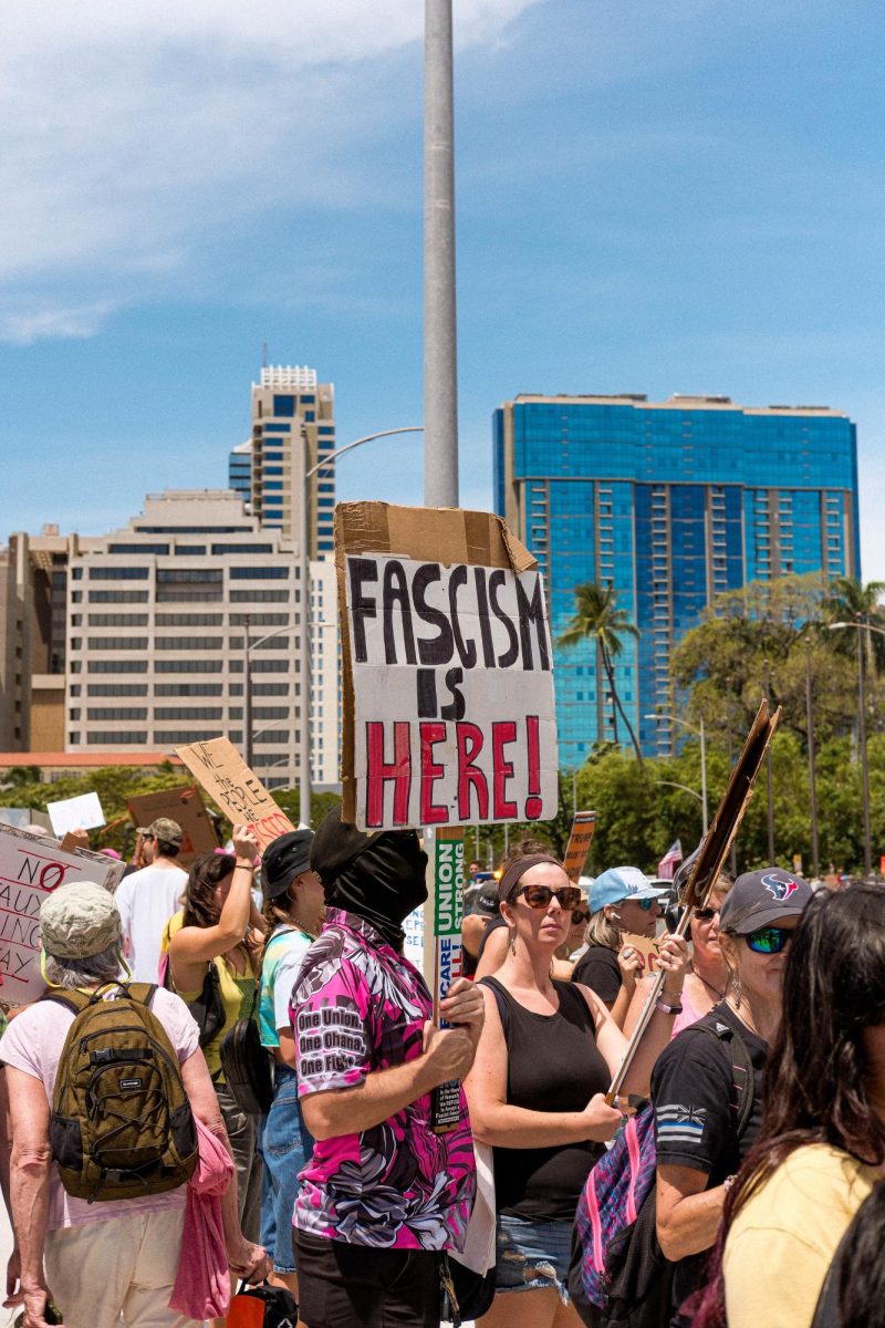 “Fascism is Here” sign is waved by a masked protester.